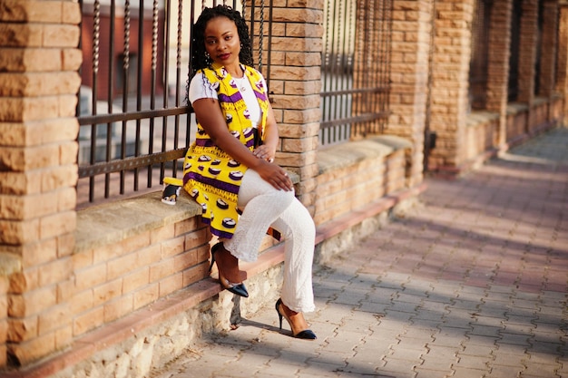 Femmes afro-américaines élégantes en veste jaune posées dans la rue avec une boisson chaude dans une tasse en papier jetable