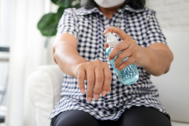 Photo femmes âgées asiatiques portant des masques blancs vaporisez de l'alcool sur vos mains pour nettoyer et prévenir le coronavirus le concept de patients restant à la maison