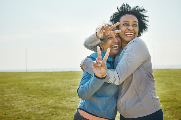 Les femmes âgées câlin et fitness signe de la main de paix et portrait avec des amis énergie et ludique en plein air Bonne amitié des femmes et cool avec des vêtements de sport dans l'exercice du parc et s'amuser ensemble