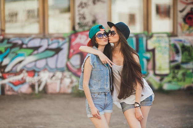 Femmes amis embrassant au mur urbain