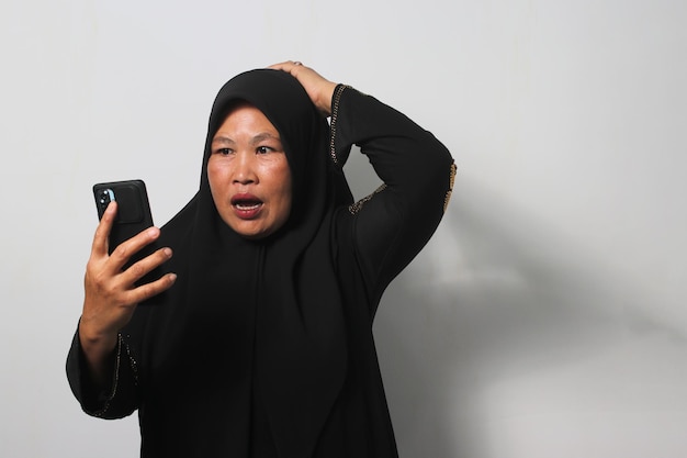 Les femmes asiatiques d'âge moyen portant le hijab se sentent tristes en lisant de mauvaises nouvelles sur leur téléphone portable