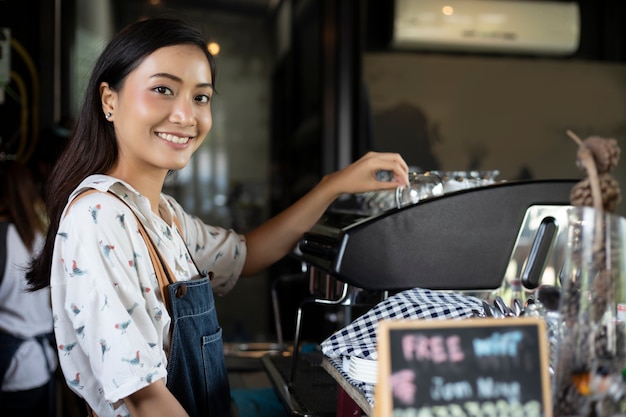 Femmes asiatiques Barista souriant et utilisant une machine à café dans un comptoir de café