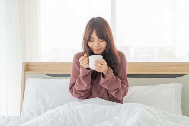 Femmes asiatiques, boire du café sur le lit le matin