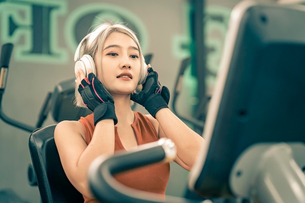 Photo femmes asiatiques en bonne santé écoutant de la musique avec un casque pendant l'exercice dans la salle de fitness