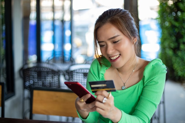 Femmes asiatiques buvant du café dans un café et faisant des achats en ligne et payant avec une carte de crédit sur des téléphones intelligents