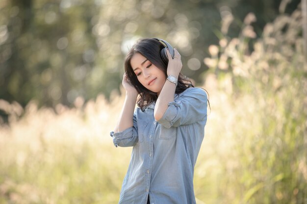 Femmes asiatiques avec un casque d&#39;écoute de musique numérique Bluetooth dans le parc