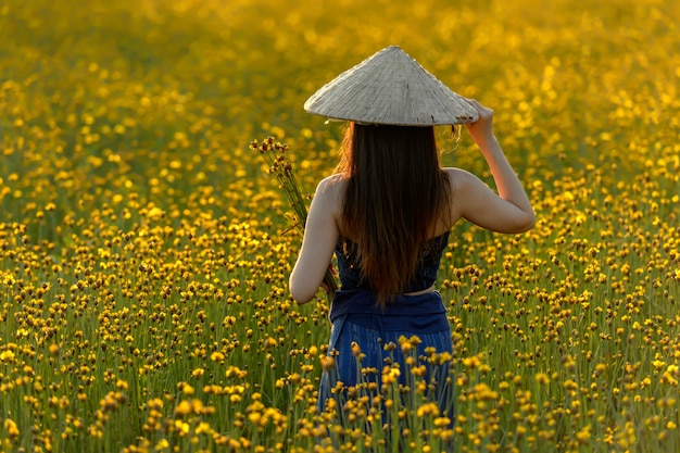 Femmes asiatiques Debout dans un beau champ de fleurs jaunes.