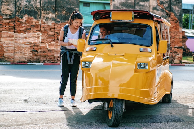 Les femmes asiatiques demandent au chauffeur de Tuk-Tuk quelle est la bonne direction sur la carte lors de l'exploration du voyage. Au parc historique d'Ayutthaya en Thaïlande.