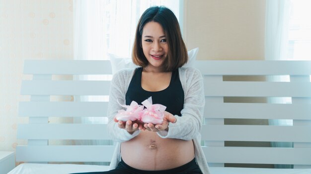 Les femmes asiatiques enceintes s&#39;amusent avec des chaussures de bébé.