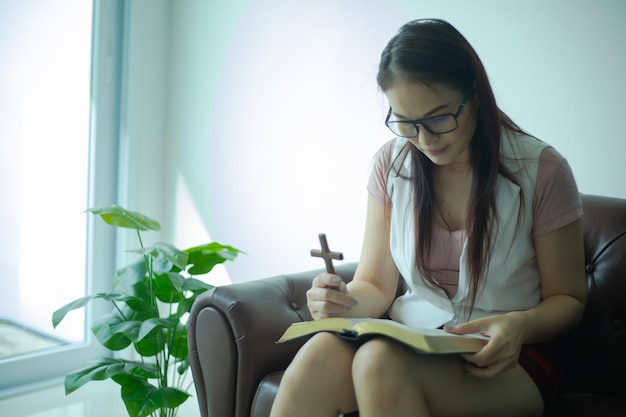 Femmes asiatiques lisant et priant avec une croix en bois à la maison.