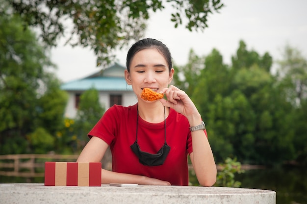 Les femmes asiatiques mangeant des ailes de poulet assis sur la table