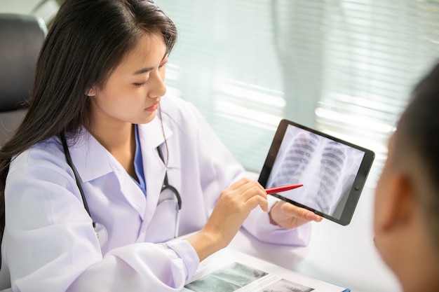 Femmes asiatiques médecin et homme discussion du patient sur les images radiographiques des résultats dans le bureau de la clinique