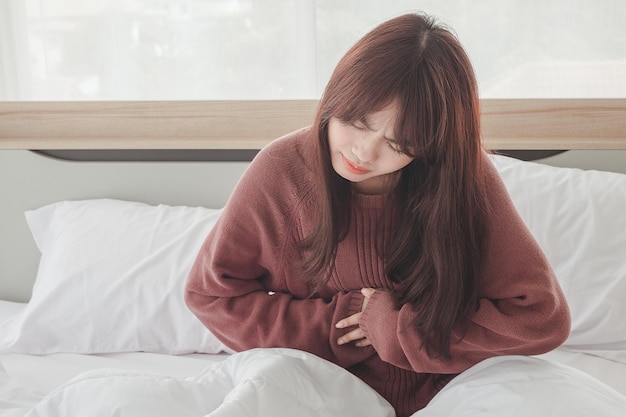 Les femmes asiatiques ont des maux d'estomac et une gêne au lit.