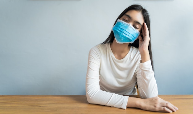 Les femmes asiatiques portant un masque se tiennent la tête à cause de maux de tête. Elle a de la fièvre et des migraines en raison du stress ou d'un sommeil tardif, d'un sommeil faible, d'un repos insuffisant dans un concept sain avec un espace de copie.