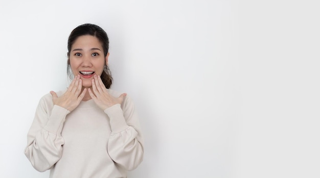 Les femmes asiatiques portent un t-shirt blanc utilisent la main touchant sa lèvre avec surprise sur les nouvelles et la promotion avec espace de copie