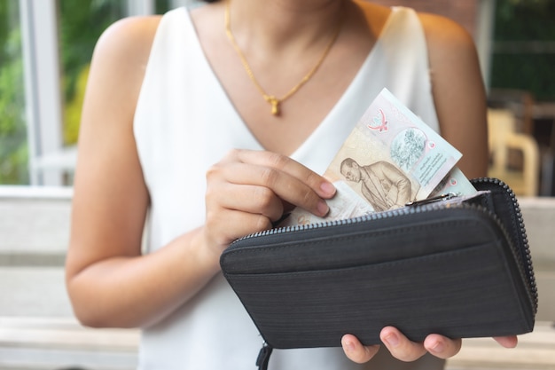 Les femmes asiatiques ramassent des billets de banque thaïlandais dans la bourse pour payer de la nourriture ou des services.