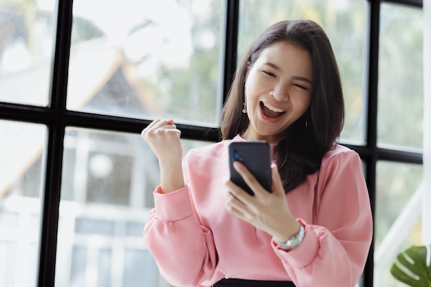 Les femmes asiatiques regardent les informations sur les téléphones portables et montrent des expressions joyeuses dirigées par une jeune femme talentueuse Le concept de gestion dirige l'entreprise de femmes leaders pour développer l'entreprise