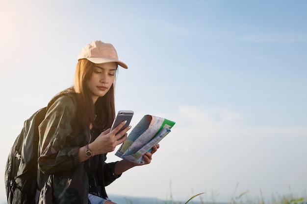 femmes asiatiques avec sac à dos brillant en regardant une carte. Vue depuis l&#39;arrière du voyageur touristique sur backgro