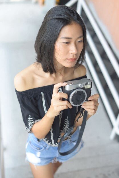 Femmes asiatiques tenant une caméra Prenez sa photo à l&#39;extérieur.