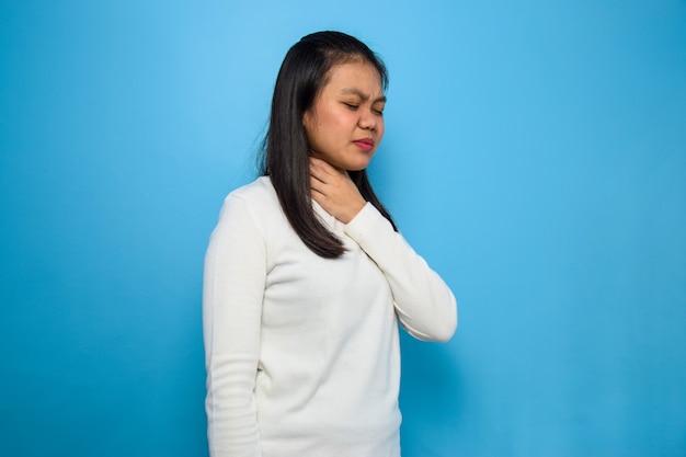 Femmes asiatiques utilisant un t-shirt blanc avec fond bleu isolé femmes maux de gorge COVID19