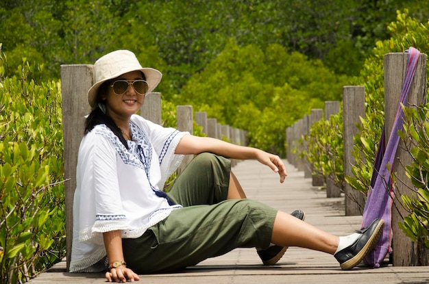 Les femmes asiatiques voyageuses s'assoient sur un pont en bois pour voyager et visiter Golden Mangrove Field nom thaïlandais Tung Prong Thong Forest ville locale de Pak Nam Prasae à Rayong Thaïlande