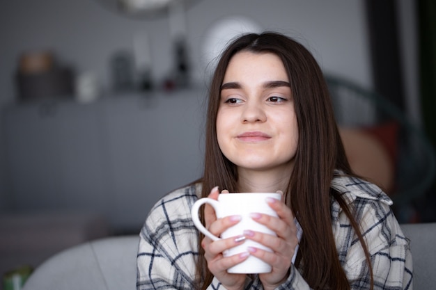 Femmes assises dans un canapé confortable avec une couverture avec du café