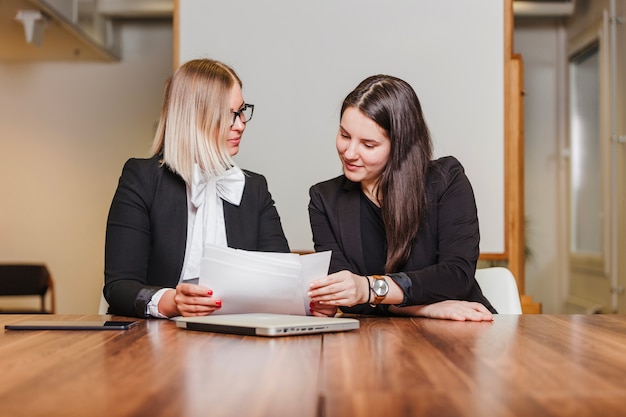 Photo femmes assises à la table en vérifiant les documents