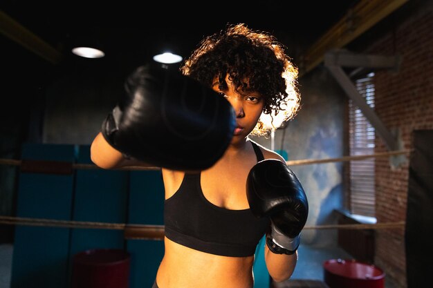 Photo femmes autodéfense girl power femme afro-américaine combattant poinçonnage avec des gants de boxe à la caméra h