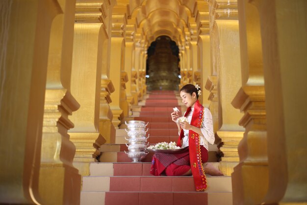 Femmes birmanes tenant des fleurs dans un temple. Jeunes filles d'Asie du Sud-Est avec une robe traditionnelle birmane visitant un temple bouddhiste