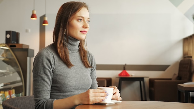 Les femmes boit une tasse de café assis dans un café