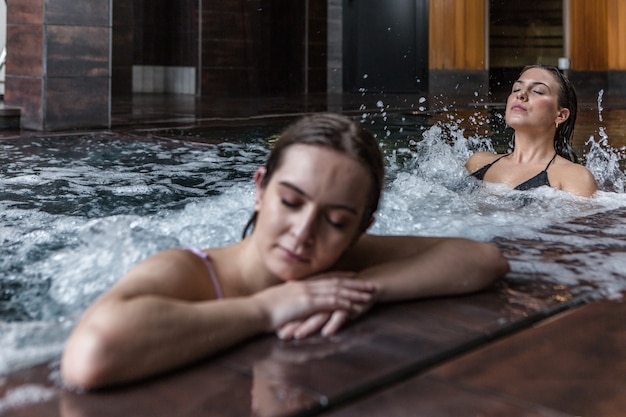 Femmes calmes bénéficiant ensemble d'hydro massage spa