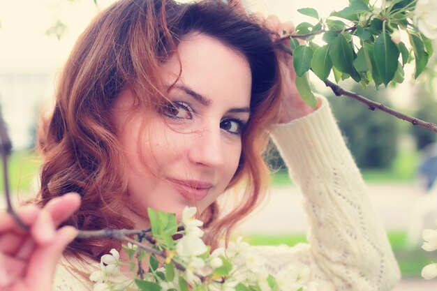 Photo femmes de cheveux rouges dans la branche de fleur de pomme