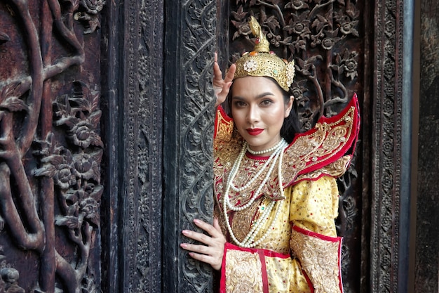 Femmes en costume traditionnel Mandalay debout par la porte en bois