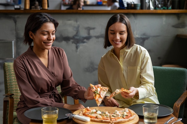 Photo femmes à coup moyen mangeant une délicieuse pizza