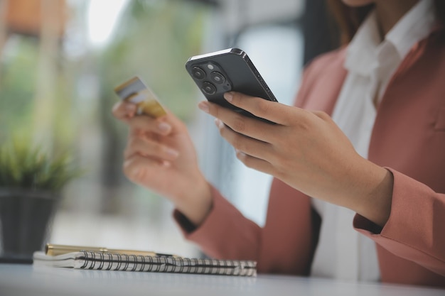 Femmes détenant une carte de crédit et utilisant des smartphones à la maison