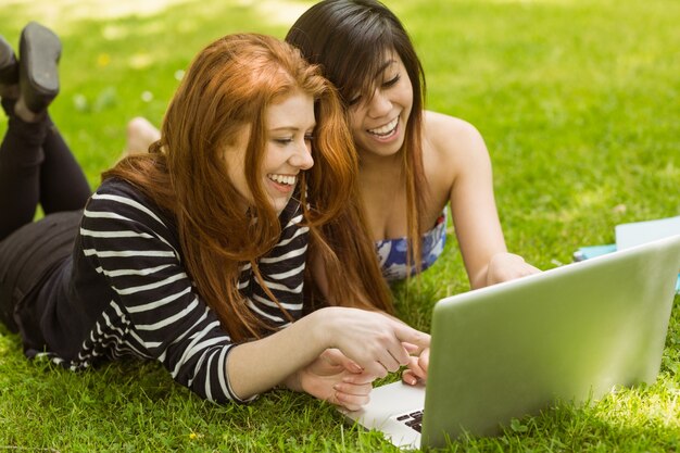 Femmes détendues heureux utilisant l&#39;ordinateur portable dans le parc