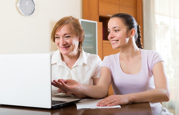Femmes avec des documents financiers et un ordinateur portable à table