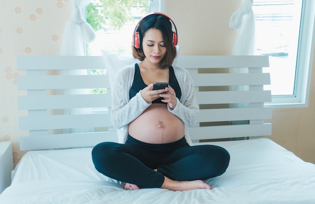 Les femmes enceintes écoutent de la musique et jouent à des téléphones.happily