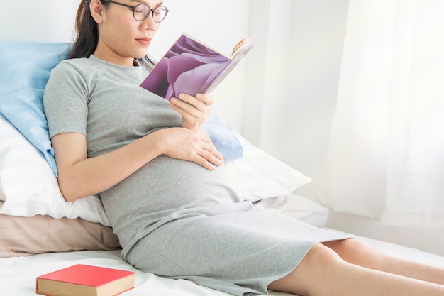 Femmes enceintes en lisant un livre sur le lit