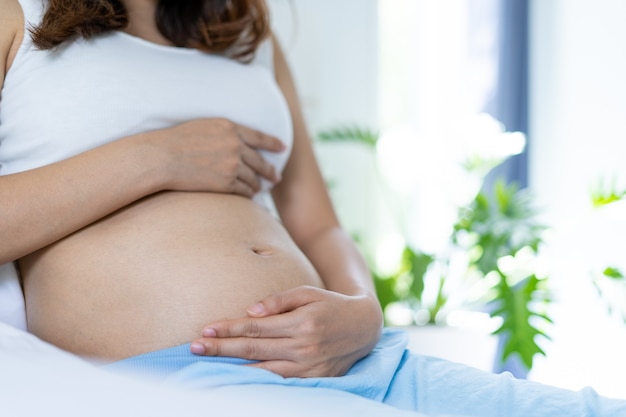 Les femmes enceintes tiennent légèrement le ventre avec les mains. Une femme enceinte est heureuse de parler à bébé. Concept d'amour mère et fils