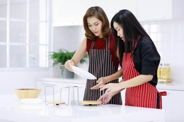 Femmes ethniques souriantes préparant un porte-serviettes tout en servant la table dans la cuisine à la maison.