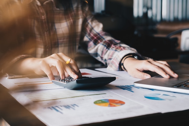 Femmes examinant des données dans des tableaux et des graphiques financiers avec une calculatrice et un ordinateur portable