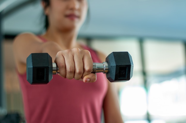 Femmes exerçant dans la salle de gym. Position de levage de poids de main tenant un haltère en avant de posture forte. concept d'exercice pour maintenir une bonne santé. faire de l'exercice à la maison