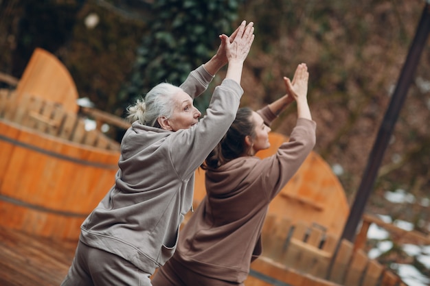 Femmes faisant des exercices de sport et de remise en forme à l'extérieur. Jeune et senior femme âgée échauffement et yoga au glamping. Mère et fille zen comme des vacances de remise en forme modernes.