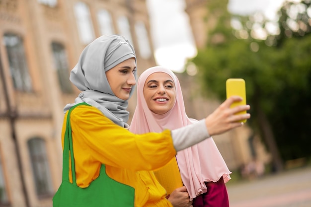 Femmes faisant selfie. Belles jeunes femmes musulmanes portant des hijabs faisant du selfie près de l'université