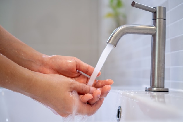 Les femmes font couler l'eau pour se laver les mains dans la salle de bain. Lavage fréquent des mains pour aider à nettoyer, réduire l'accumulation de bactéries et de virus.