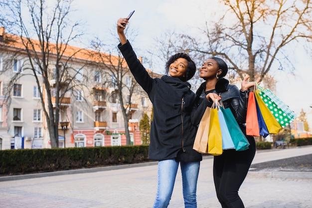 Les femmes font des selfies avec des sacs à provisions dans la ville