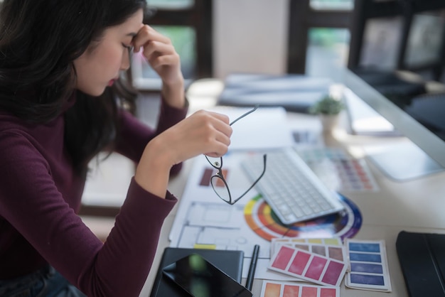 Photo les femmes graphistes indépendantes massent le nez pour se reposer avec des maux de tête et du stress après avoir dessiné le logo de la marque et travaillé à la conception sur le design graphique avec des équipements technologiques dans le studio à domicile