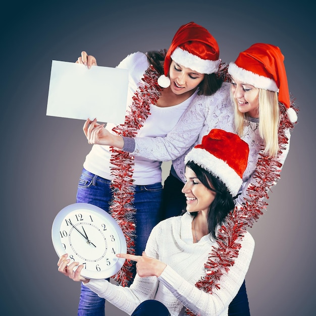 Femmes heureuses en costume de père noël avec horloge et achats de noël