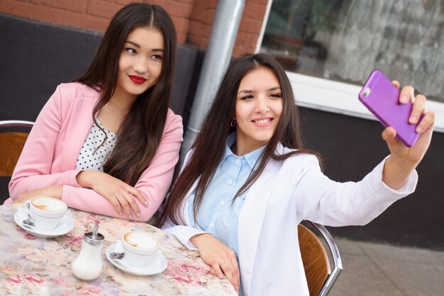 Femmes heureuses prenant photo selfie sur smartphone à l'extérieur